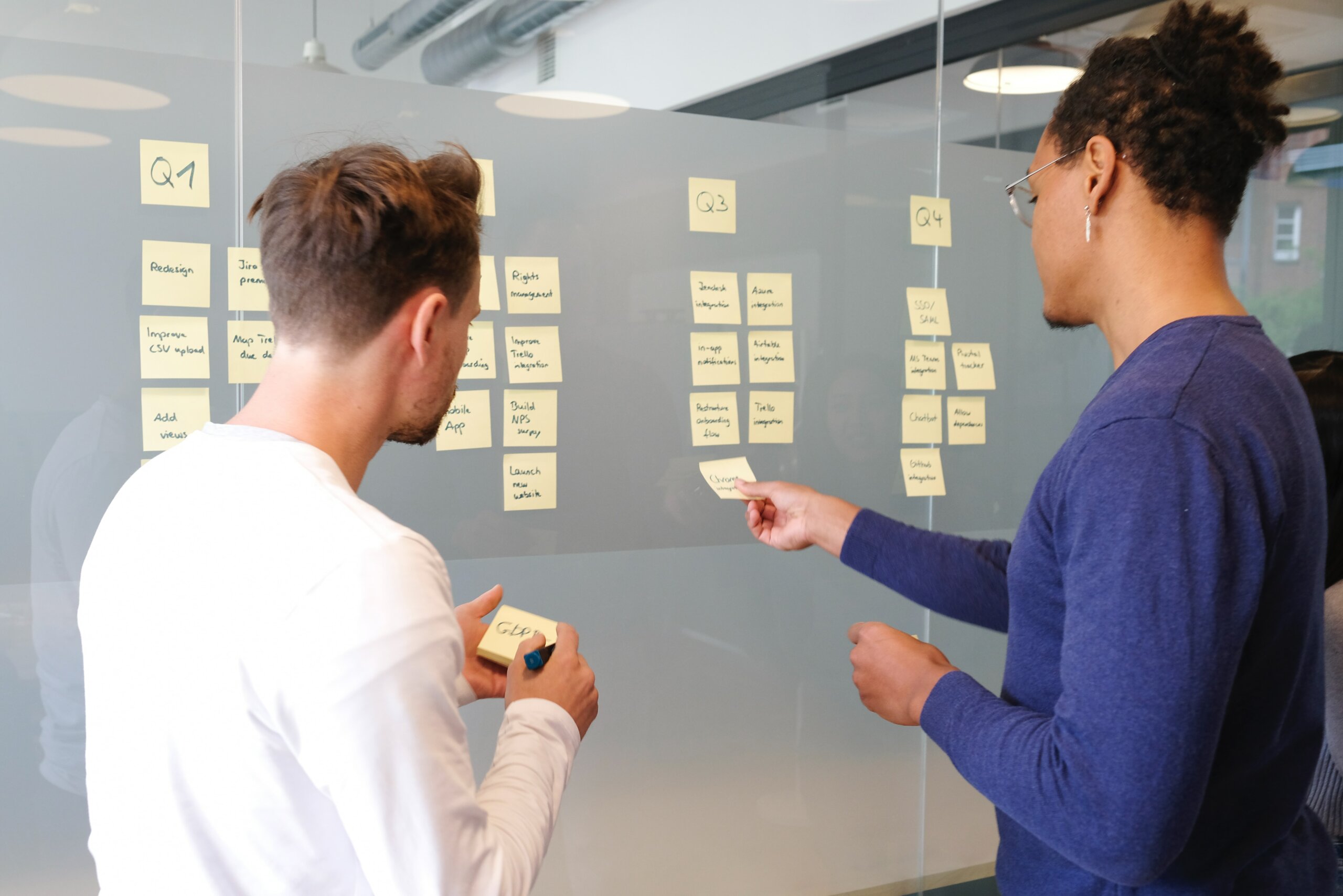 Two designers examining post-its on a wall